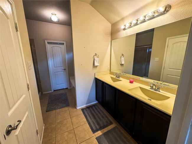 Bathroom featuring tile patterned flooring, double vanity, a sink, and lofted ceiling | Image 19