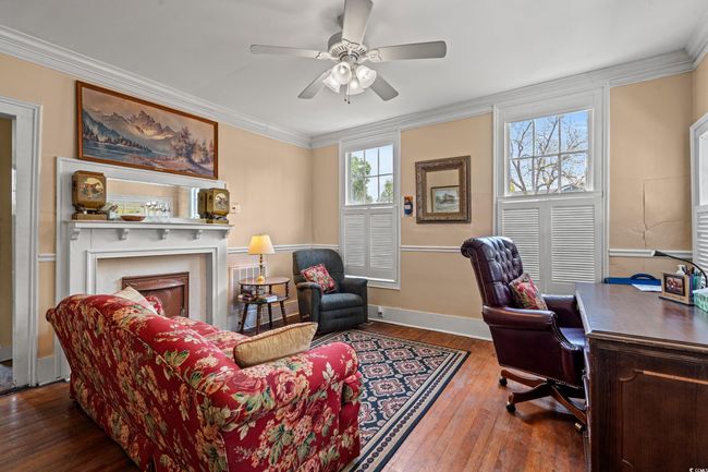 Office space with wood-type flooring, ornamental molding, ceiling fan, and a fireplace | Image 39