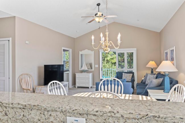 Carpeted dining space featuring a ceiling fan, a chandelier, high vaulted ceiling, and baseboards | Image 7