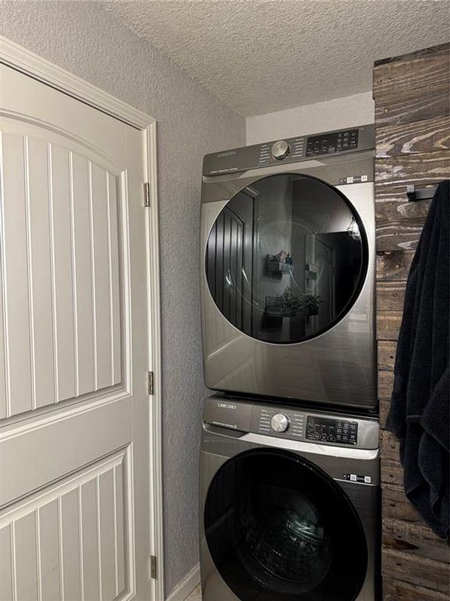 Laundry room featuring stacked washer and clothes dryer and a textured ceiling | Image 10