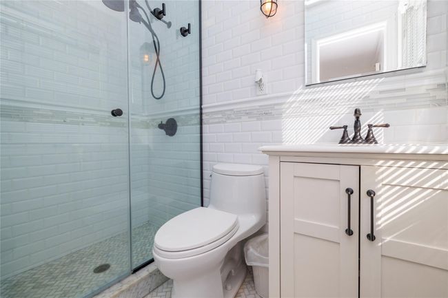 Bathroom with a stall shower, toilet, vanity, and tile walls | Image 20