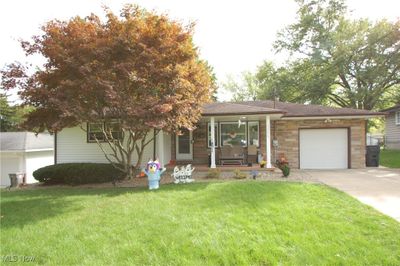 View of front of property with a front lawn, a porch, and a garage | Image 1