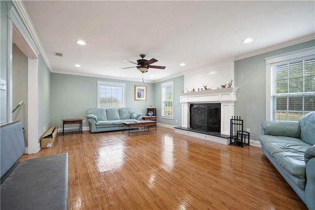 Living area with visible vents, crown molding, light wood-style floors, and a ceiling fan | Image 6
