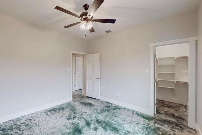 Unfurnished bedroom with carpet, a ceiling fan, visible vents, a spacious closet, and baseboards | Image 12