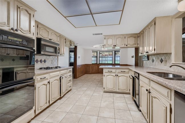 Kitchen featuring appliances with stainless steel finishes, a peninsula, wainscoting, wine cooler, and a sink | Image 15