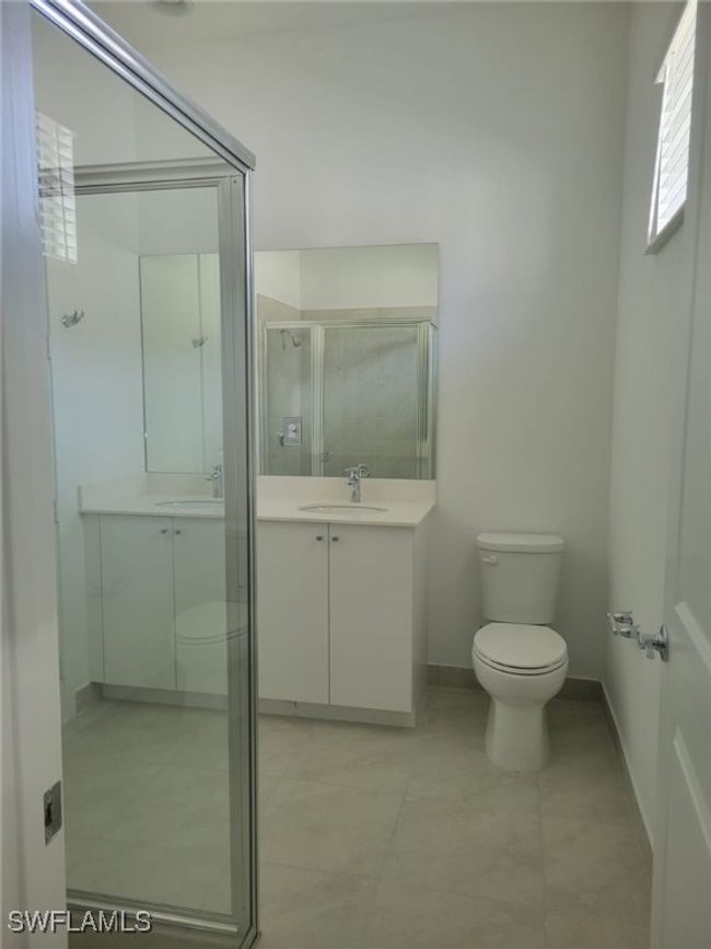 Full bath featuring toilet, a stall shower, vanity, baseboards, and tile patterned flooring | Image 22