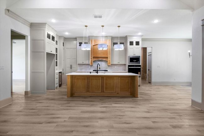 Kitchen featuring brown cabinets, light wood-style floors, glass insert cabinets, recessed lighting, and crown molding | Image 14