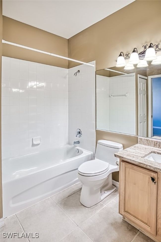Full bathroom featuring toilet, tile patterned floors, vanity, and tiled shower / bath combo | Image 38