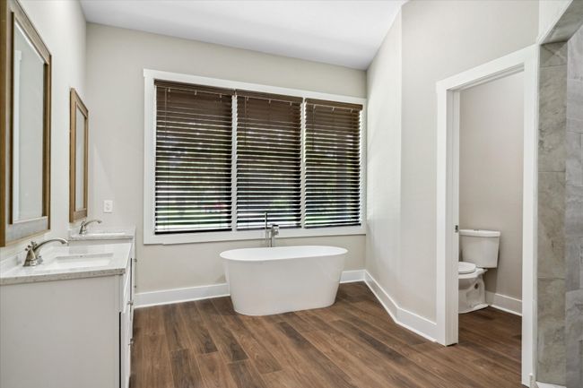 Bathroom with double vanity, toilet, wood finished floors, and a freestanding bath | Image 15