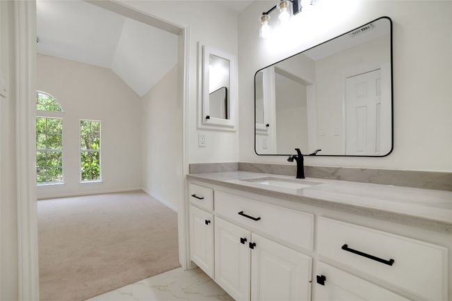 Bathroom with marble look tiles, vanity, and vaulted ceiling | Image 27