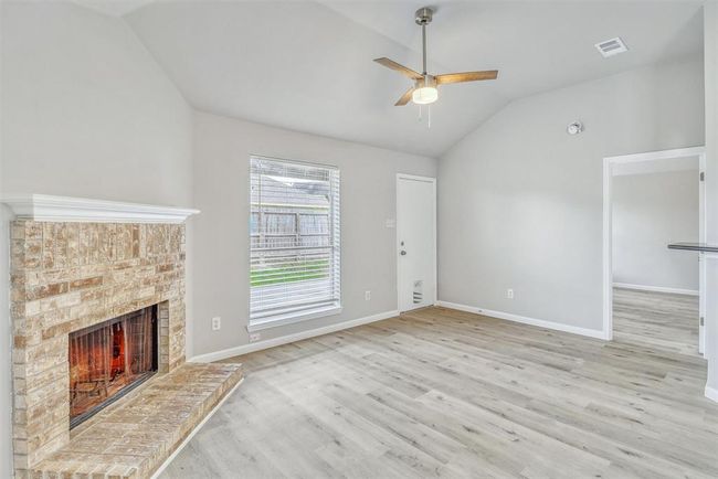 Cozy up next to the charming brick fireplace with a custom mantle, all while enjoying serene views of the backyard through a floor-to-ceiling window that fills the room with natural light. | Image 7