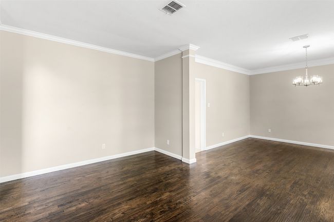 Unfurnished room with crown molding, visible vents, a notable chandelier, and dark wood-type flooring | Image 6