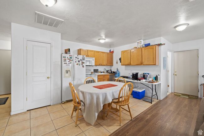 Kitchen with light wood finished floors, white appliances, visible vents, and light countertops | Image 43