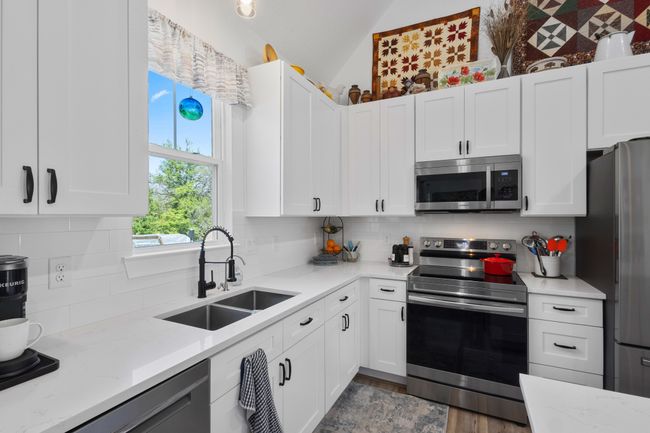 Kitchen featuring stainless steel appliances, white cabinetry, a sink, and decorative backsplash | Image 14