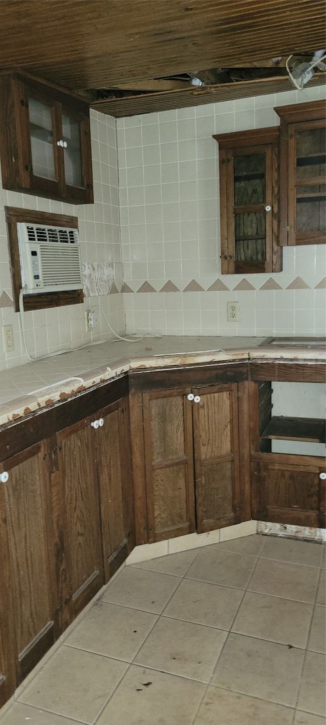 Laundry room with tile counters, tasteful backsplash, light tile patterned flooring, and glass insert cabinets | Image 31