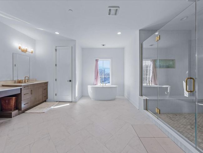 Bathroom with a freestanding tub, vanity, a shower stall, marble finish floor, and visible vents | Image 14