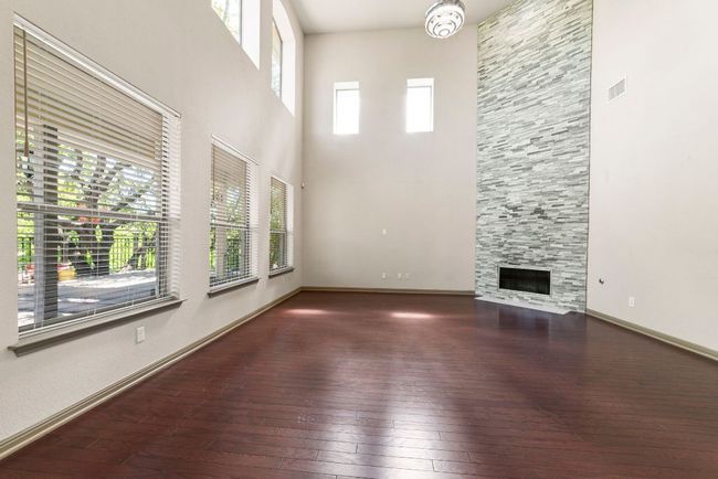 Unfurnished living room featuring hardwood / wood-style floors, plenty of natural light, a high ceiling, and a fireplace | Image 13