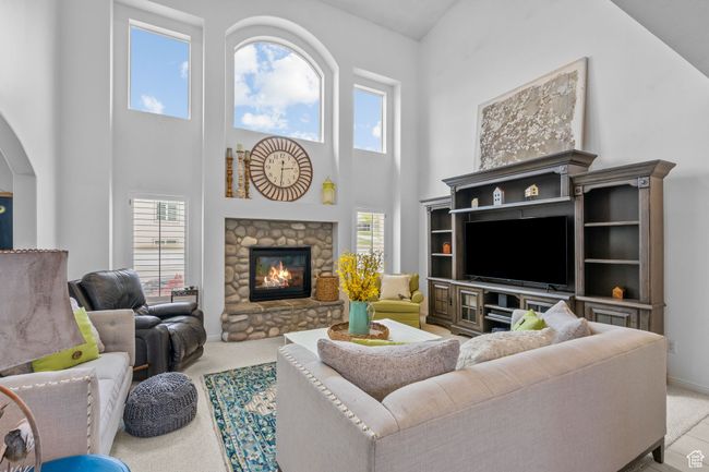 Carpeted living room featuring arched walkways, a high ceiling, baseboards, and a fireplace | Image 11