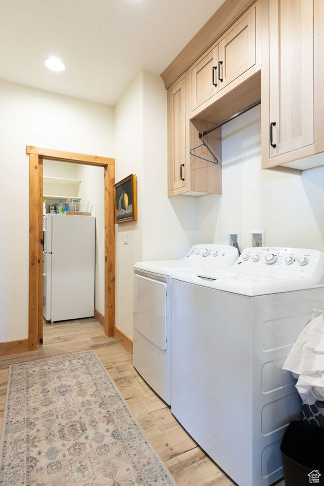 Laundry area with light wood-style floors, cabinet space, baseboards, and washer and dryer | Image 40