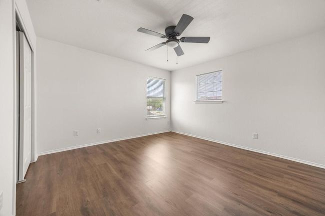 Unfurnished bedroom with baseboards, dark wood-style floors, a closet, and a ceiling fan | Image 16