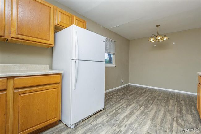 Kitchen featuring freestanding refrigerator, wood finished floors, a chandelier, and light countertops | Image 8