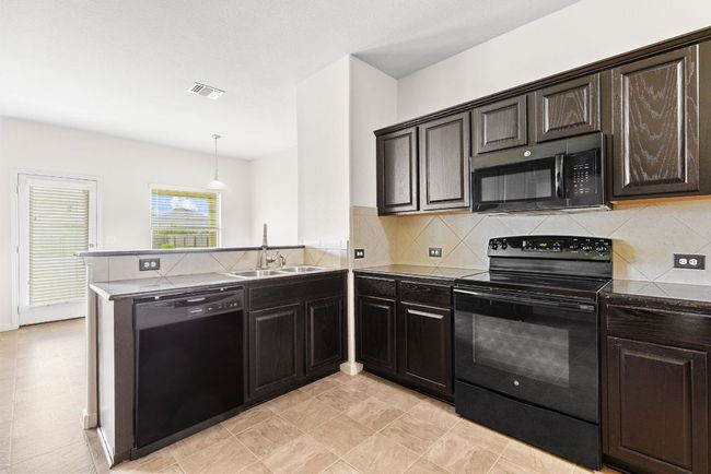 Kitchen with black appliances, a sink, a peninsula, and decorative backsplash | Image 21