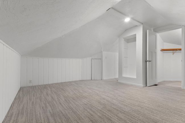 Attic features paneled walls, built-in storage niches and a walk-in closet | Image 23