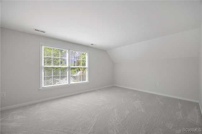 Bedroom with new carpet featuring baseboards, visible vents, light carpet, and lofted ceiling | Image 29