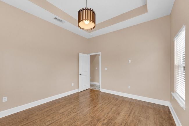 Empty room featuring a raised ceiling, wood finished floors, and a chandelier | Image 28