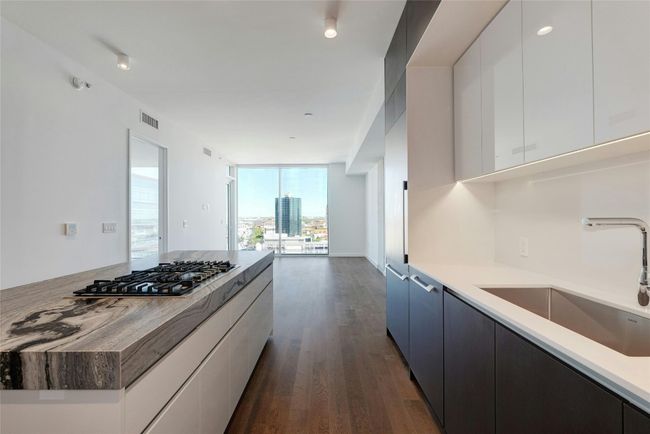Kitchen featuring wood-type flooring, stainless steel gas stovetop, white cabinetry, visible vents, and a sink | Image 14