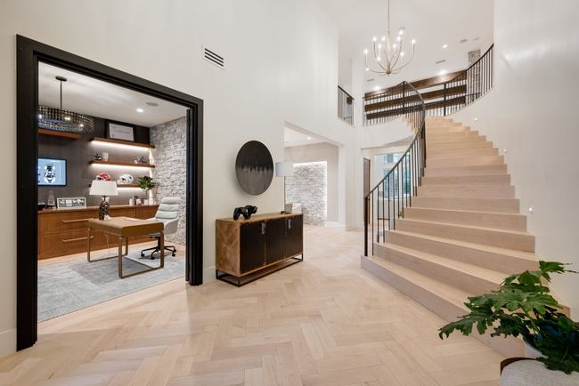 Foyer featuring a towering ceiling, stairway, a chandelier, and baseboards | Image 4