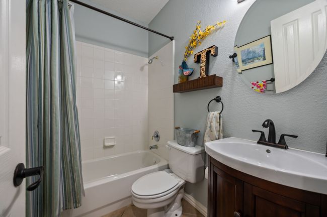 Bathroom with shower / bath combo with shower curtain, a textured wall, vanity, and tile patterned floors | Image 19