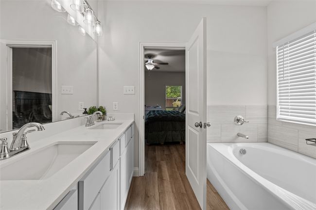 Ensuite bathroom with wood finished floors, a garden tub, ceiling fan, and double vanity | Image 21