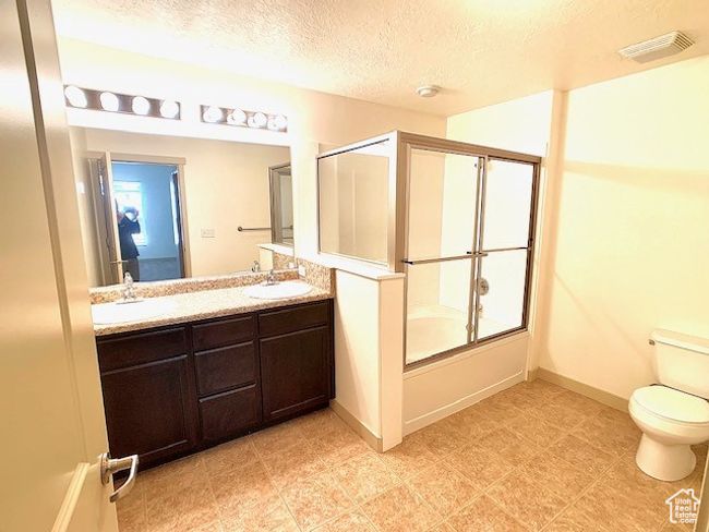 Bathroom featuring double vanity, a textured ceiling, and combined bath / shower with glass door | Image 9