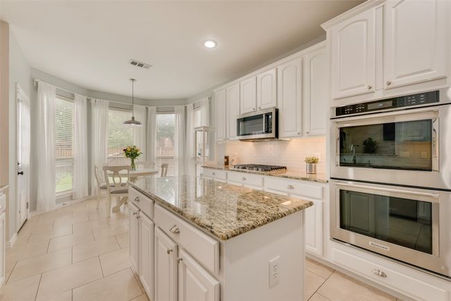 Kitchen featuring appliances with stainless steel finishes, light tile patterned flooring, a kitchen island, recessed lighting, and decorative backsplash | Image 16