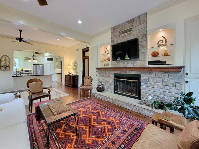 This elegant fireplace features a stunning floor-to-ceiling stone surround and illuminated shelves, perfect for showcasing your art and valuables. | Image 14