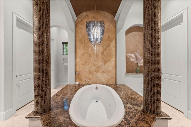 Grand primary bath featuring a jetted tub as the centerpiece, framed by elegant columns for a luxurious, spa-like experience | Image 28