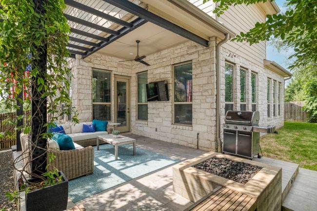 View of patio featuring an outdoor living space with a fire pit, a ceiling fan, fence, and grilling area | Image 33