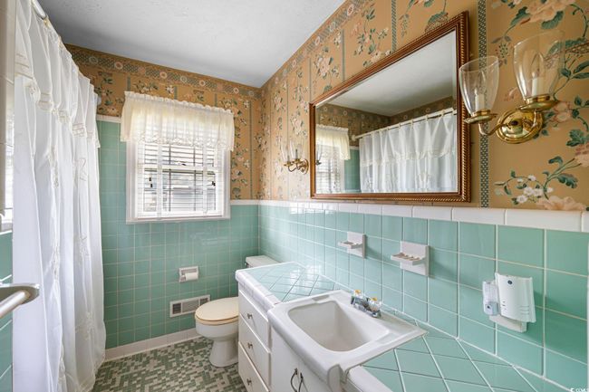 Bathroom with wallpapered walls, toilet, tile walls, wainscoting, and vanity | Image 19