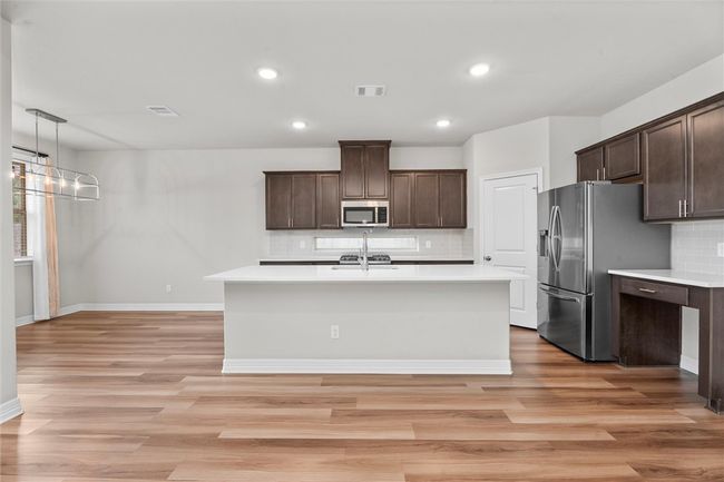 Kitchen featuring stainless steel appliances, dark brown cabinetry, decorative backsplash, light countertops, and recessed lighting | Image 8