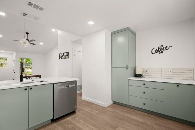Kitchen with stainless steel dishwasher, green cabinets, light wood-type flooring, light countertops, and a ceiling fan | Image 12