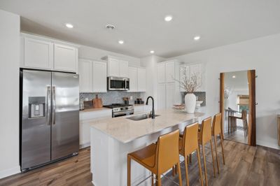 (Photo of decorated model, actual homes color and finishes will vary) A spacious kitchen with an abundance of cabinet space and a large center island providing optimal seating. | Image 1