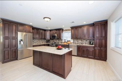 Massive Kitchen featuring high end appliances, light wood-type flooring, plenty of natural light, and a center island | Image 3