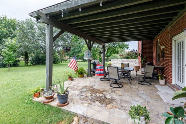 View of covered patio featuring stamped concrete, outdoor dining area and french doors leading back inside. | Image 32