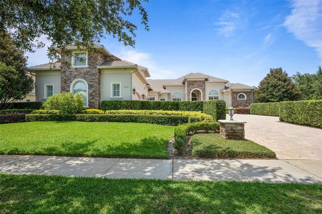Lush landscaping, manicured hedges, and elegant stone accents create a grand first impression for this custom Keene’s Pointe estate, set behind a stately paver drive. | Image 30