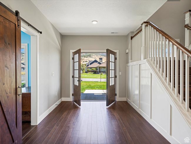 Entrance foyer featuring baseboards, dark wood-type flooring, a barn door, and a textured ceiling | Image 16