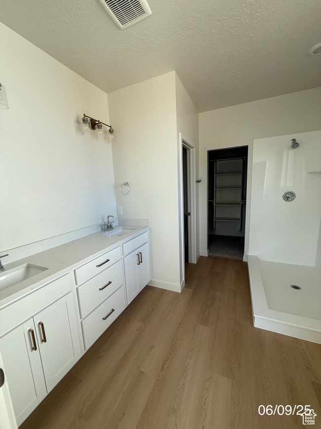 Bathroom with wood finished floors, a stall shower, a textured ceiling, and double vanity | Image 9