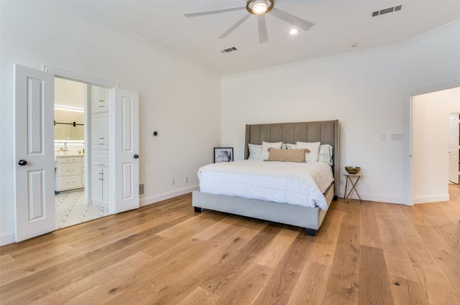Bedroom featuring light wood-type flooring, ornamental molding, baseboards, and visible vents | Image 24