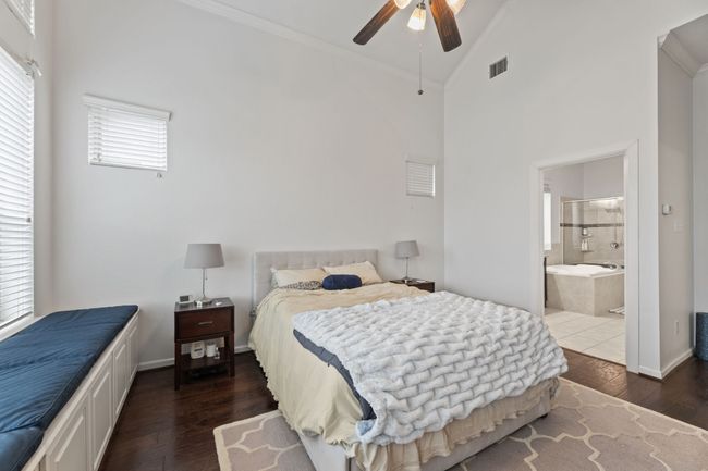 Bedroom featuring ornamental molding, wood finished floors, high vaulted ceiling, connected bathroom, and a ceiling fan | Image 21