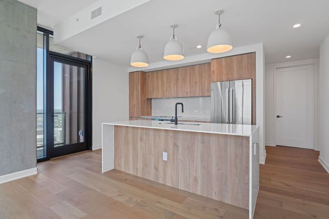 Kitchen with freestanding refrigerator, modern cabinets, backsplash, light countertops, and light wood-style flooring | Image 12
